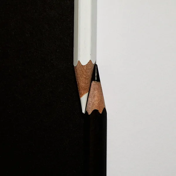 Deux crayons taillés, l'un blanc, l'autre noir